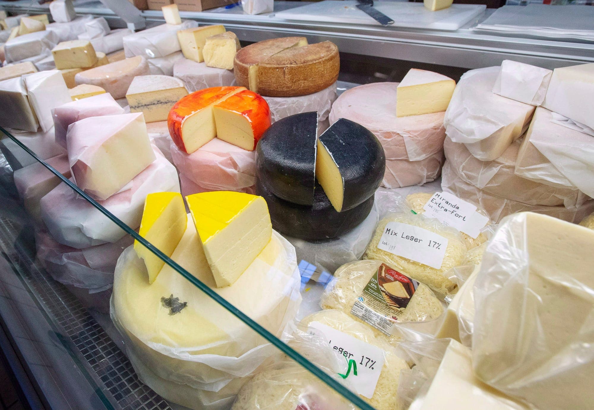 Several wheels and bags of cheese in a display case.