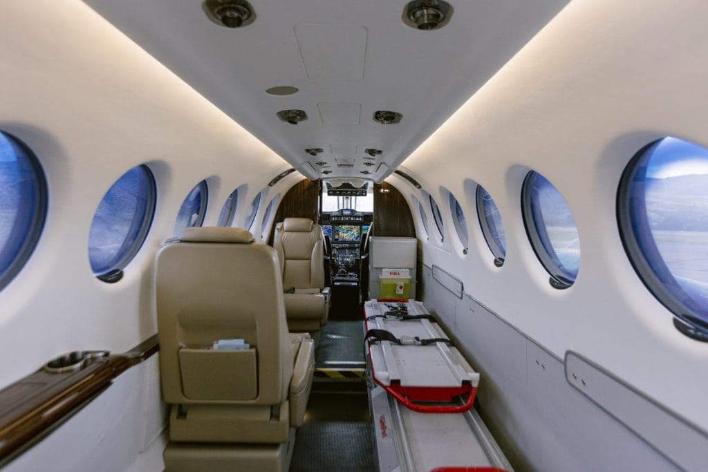 An emergency stretcher and other medical equipment lies on one side of the interior of a small airplane.