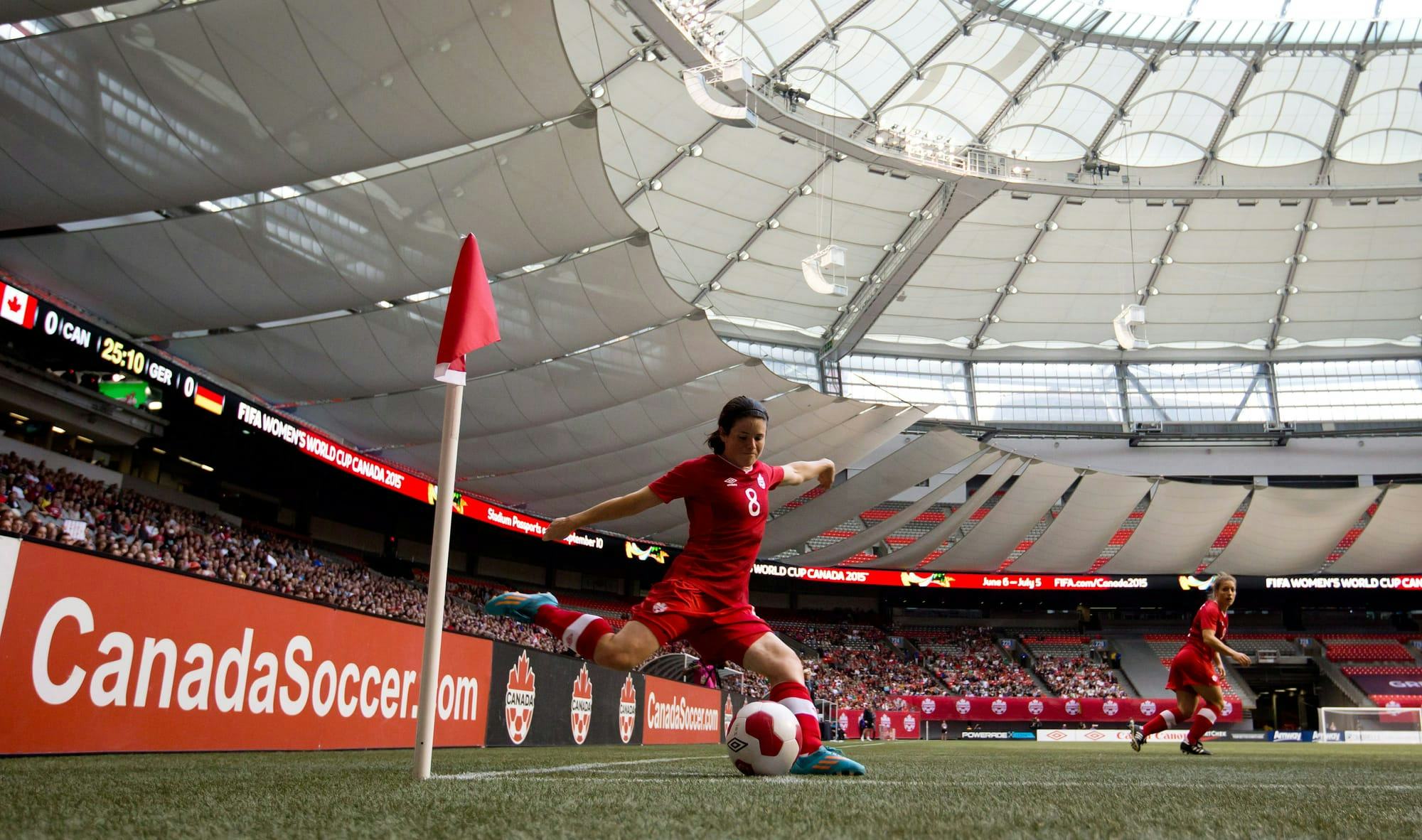 Soccer player Diana Matheson kicks a ball to her teammates from the corner of the field.
