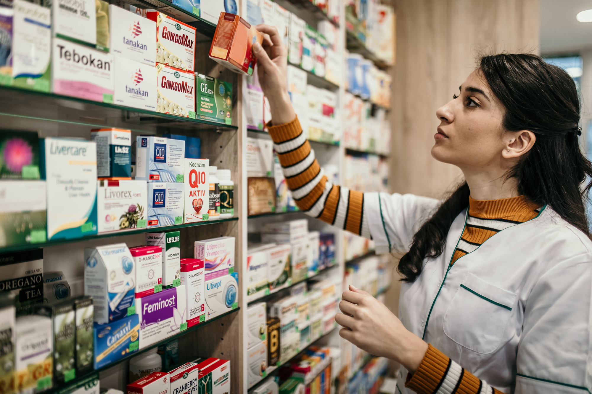 A woman shops in the vitamin aisle of a store.