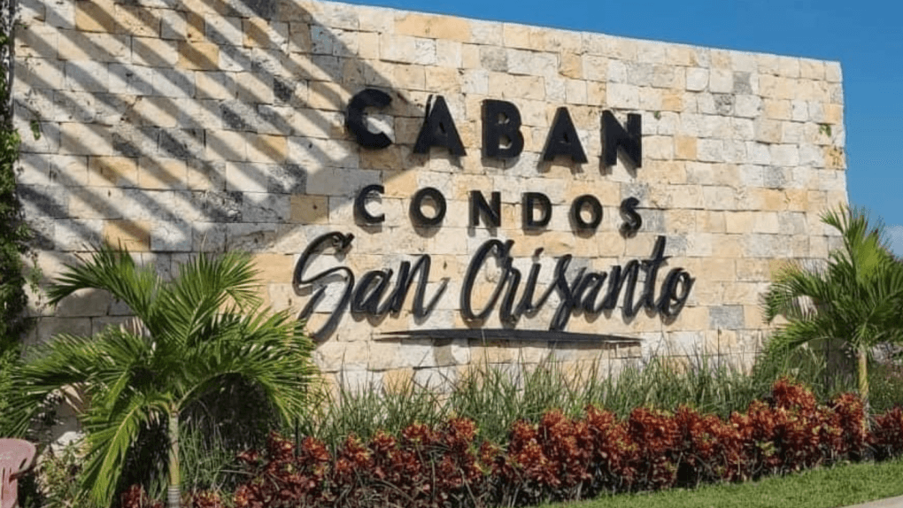 "Caban Condos San Crisanto" is spelled out in black writing on a large beige stone wall. 