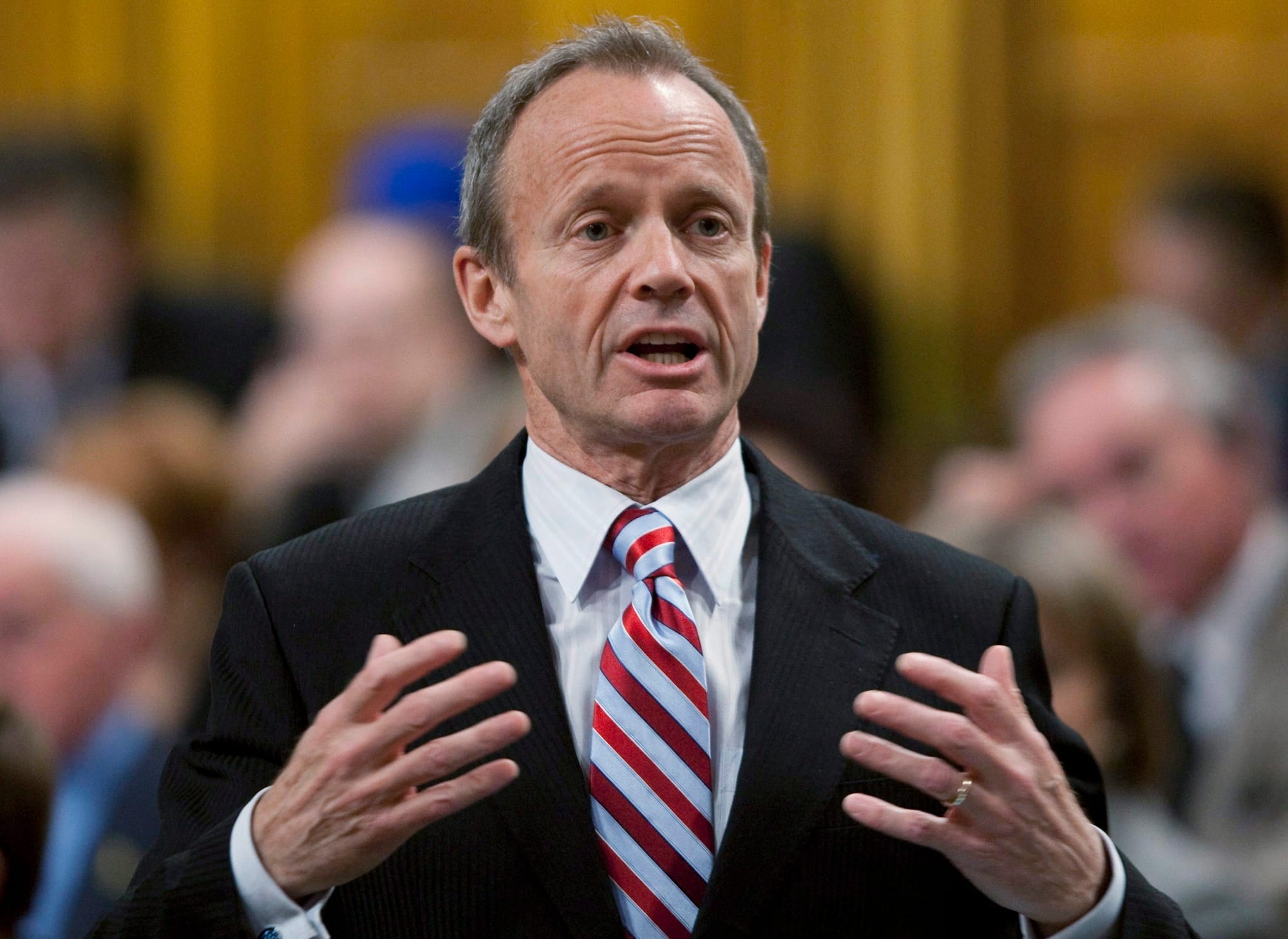 A man in a suit and striped tie gestures during debate in the House of Commons.