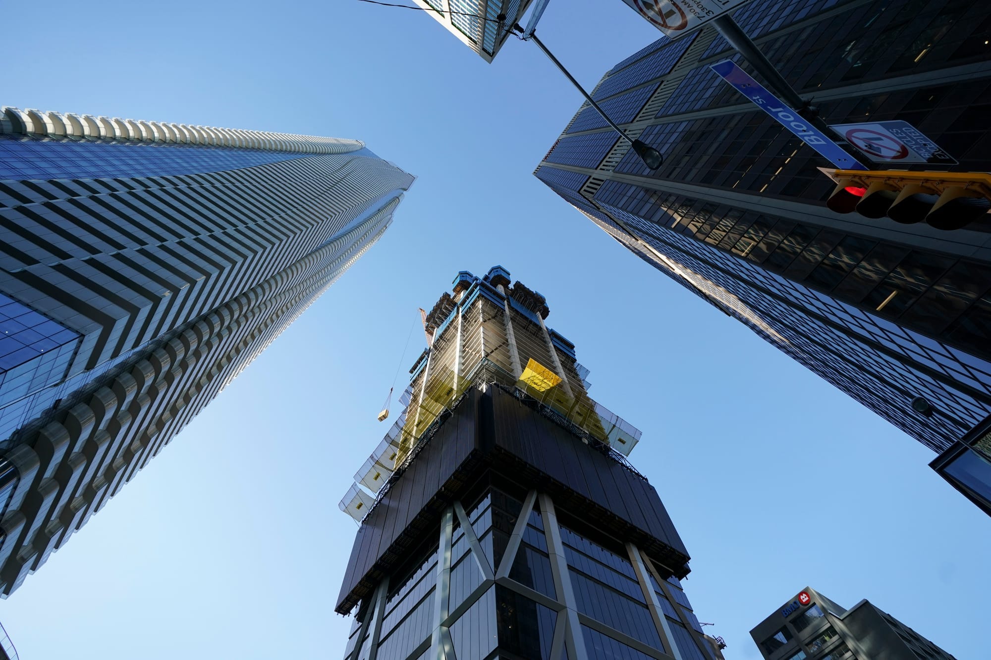 Four skyscrapers are pictured towering up from the camera's perspective against the backdrop of a blue sky.