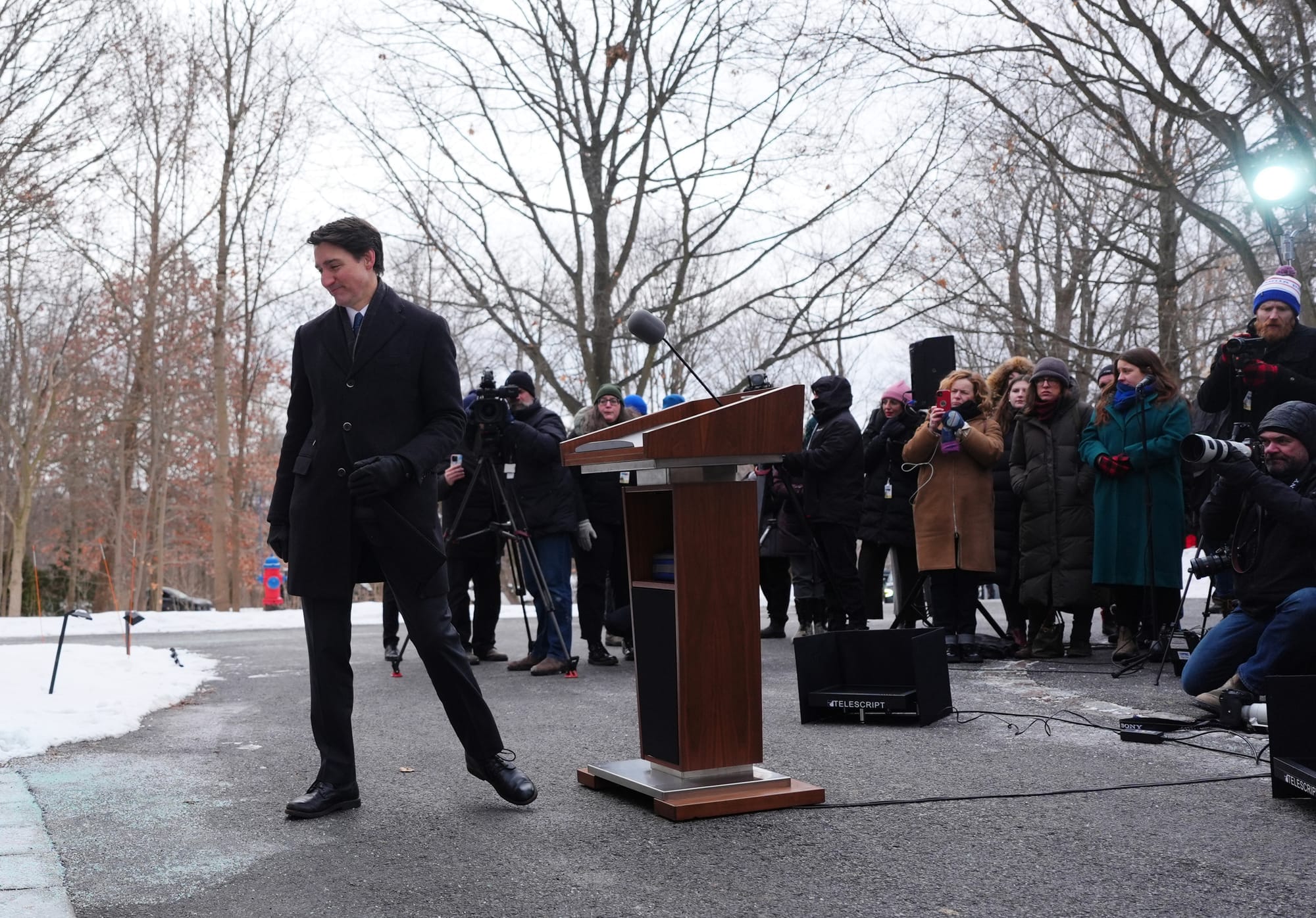 Canadian Prime Minister Justin Trudeau turns to leave a wooden podium surrounded by reporters.