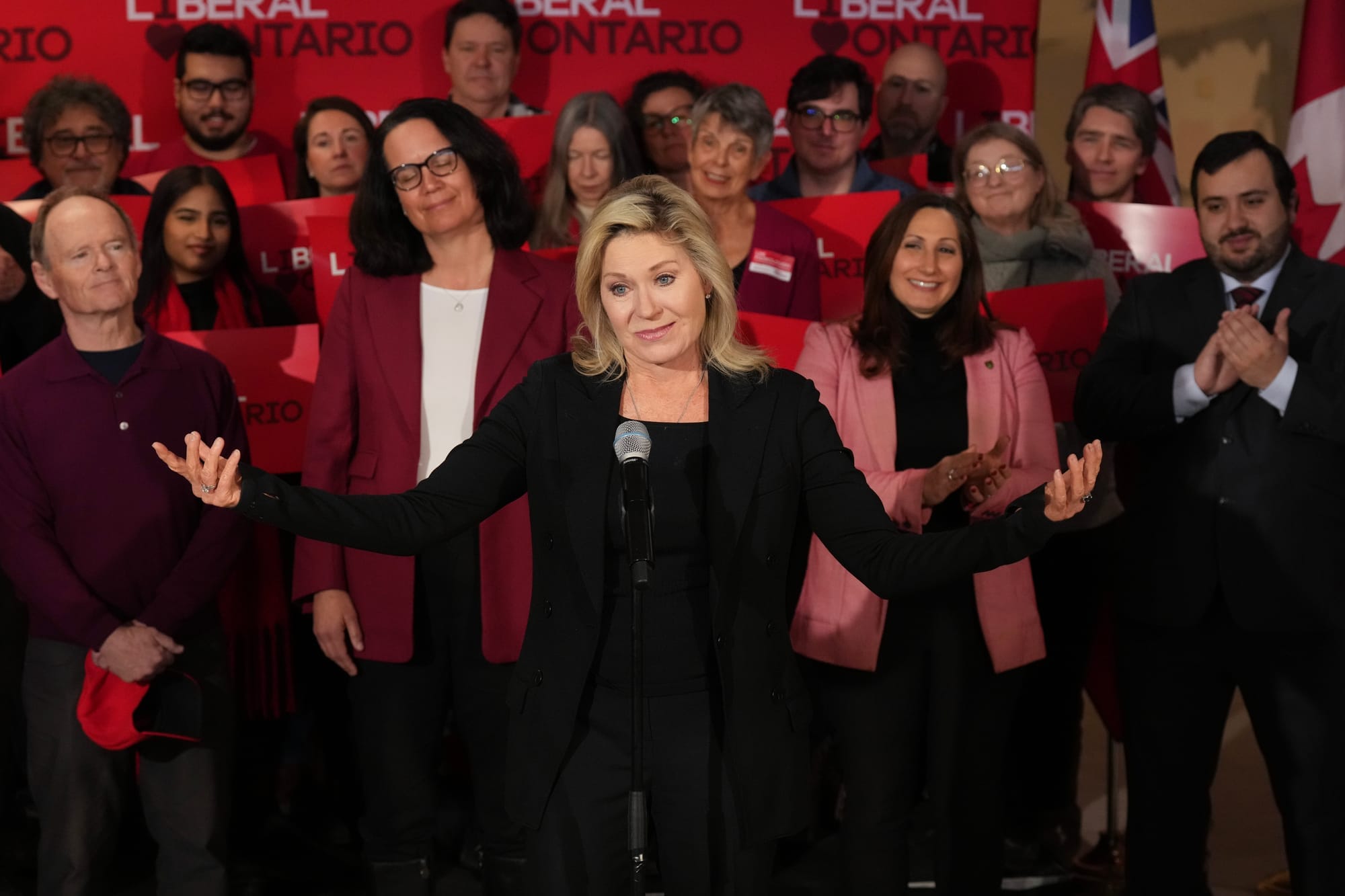 Bonnie Crombie, gestures to a crowd while supporters applaud and hold red signs in support of the Ontario Liberals. 