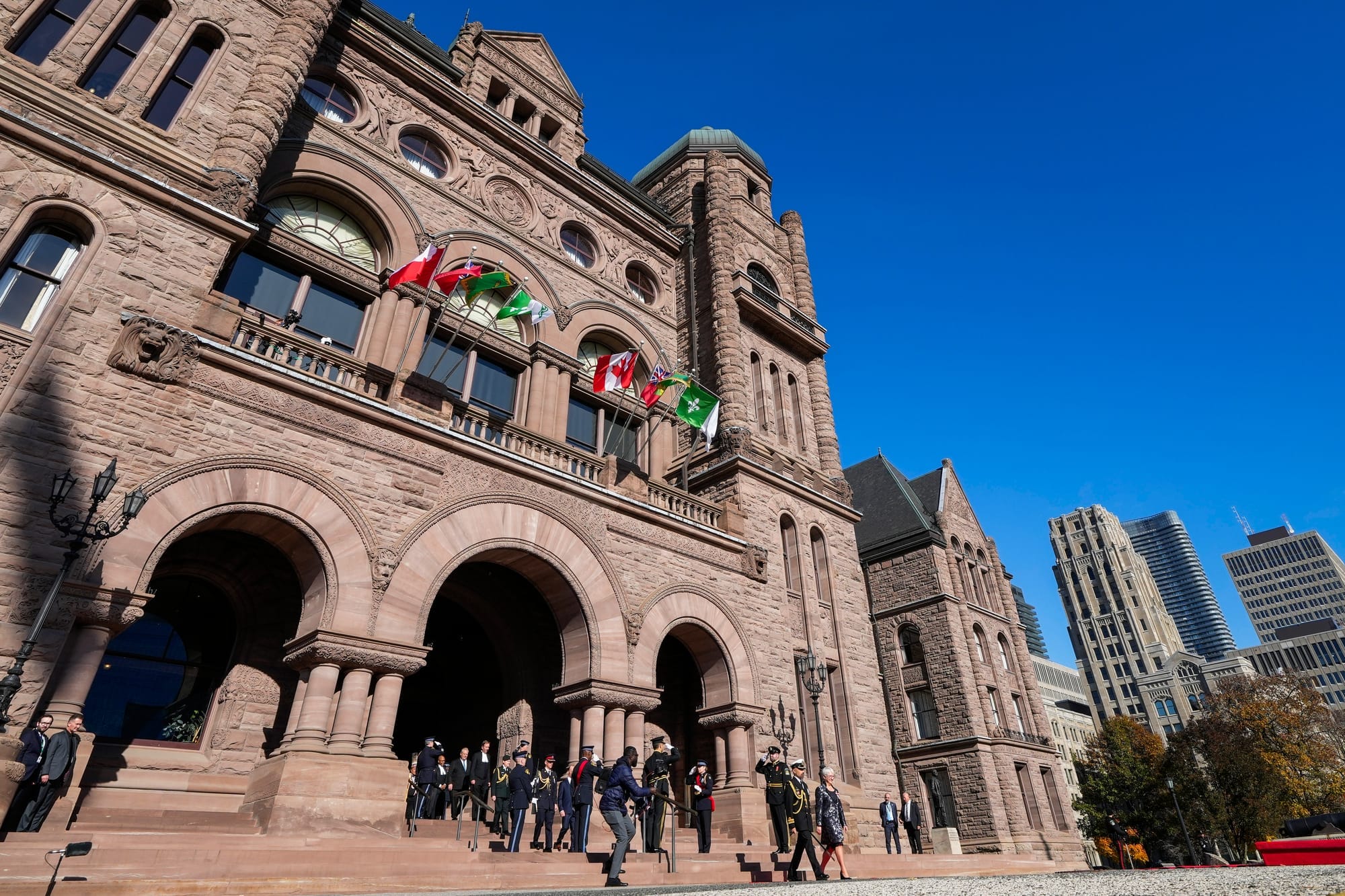 Officials walk out of the limestone building at Queen's Park in Toronto.