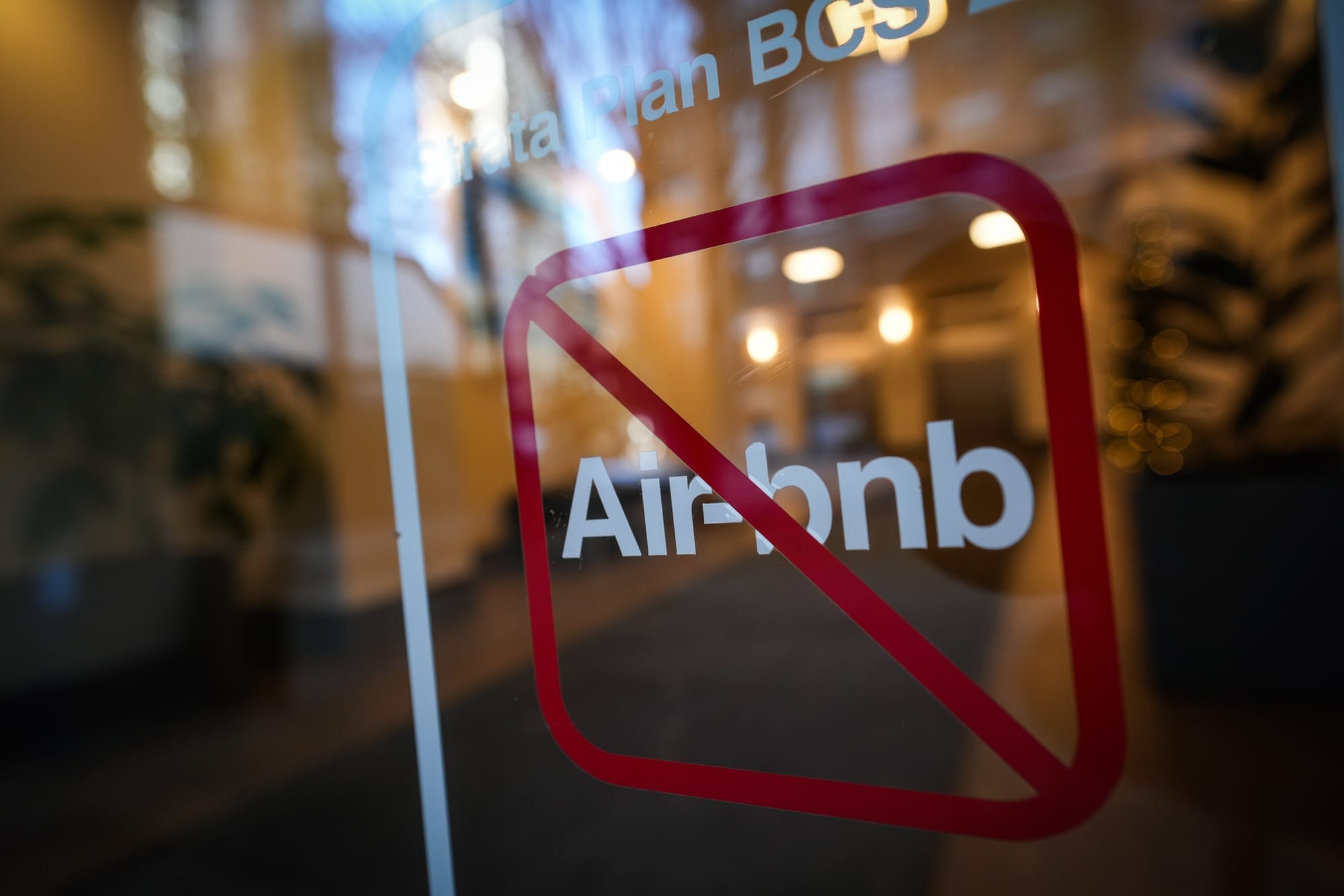 A sign on a glass window says Air-bnb with a red line through it
