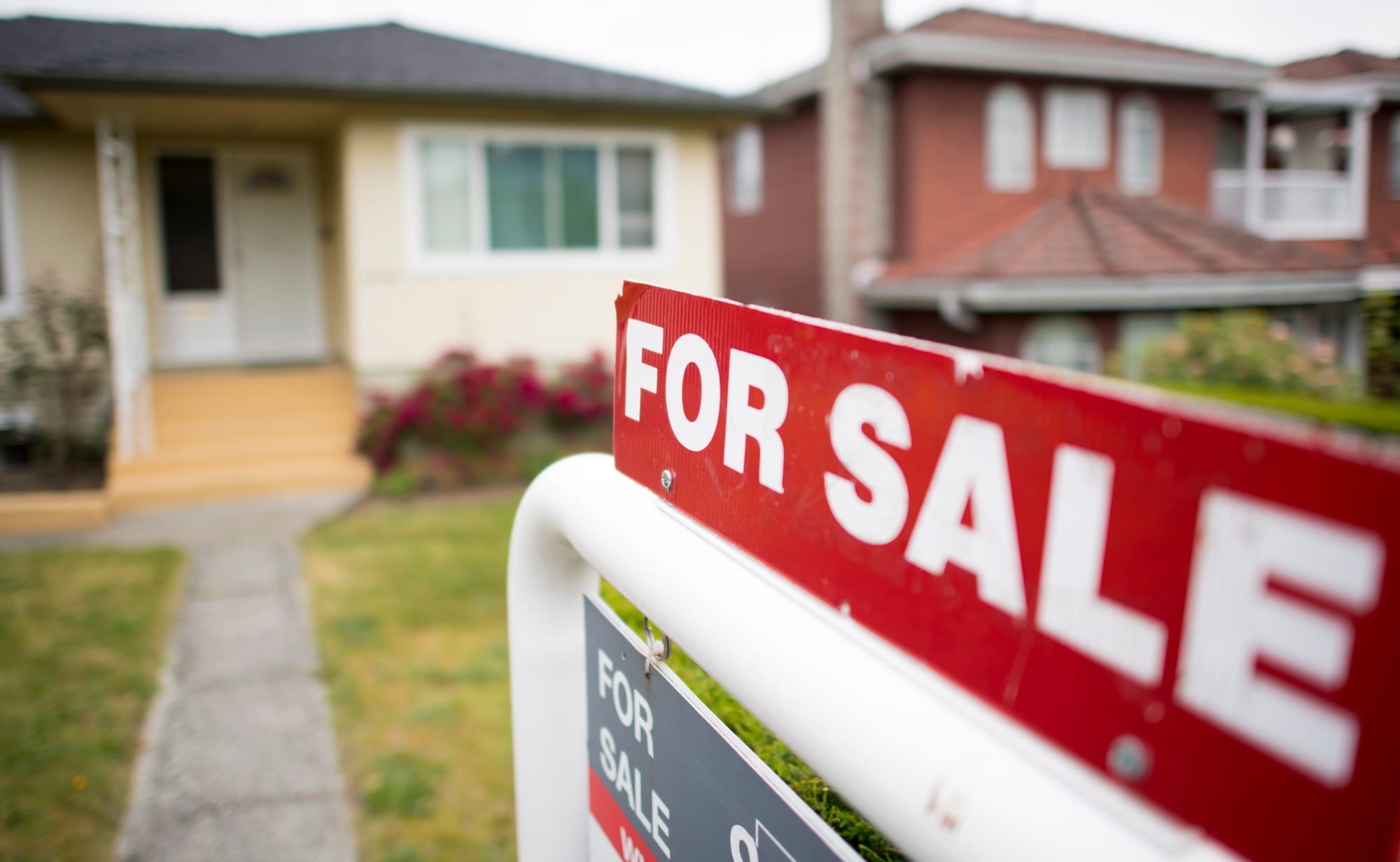 A red and white "For Sale" sign outside a residential home in Vancouver. 