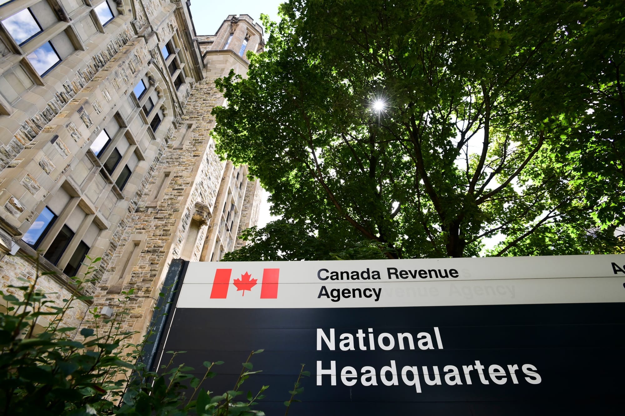 A sign for the national headquarters of the Canada Revenue Agency in Ottawa, with the building in the background.