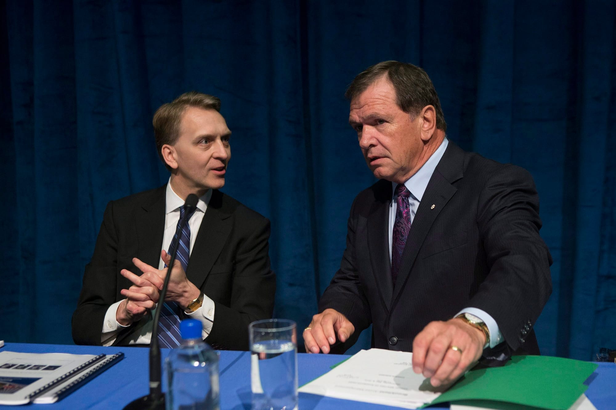 Two men wearing suits are seated next to each other at a Brookfield annual general meeting