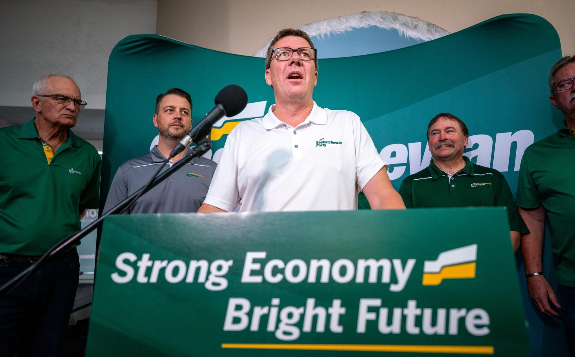 Saskatchewan Premier Scott Moe stands behind a podium that says "Strong Economy Bright Future" at a campaign stop.
