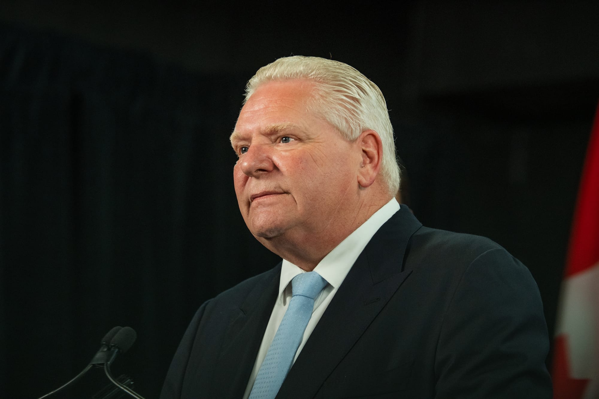 Doug Ford speaks at a press conference wearing a suit and blue tie 