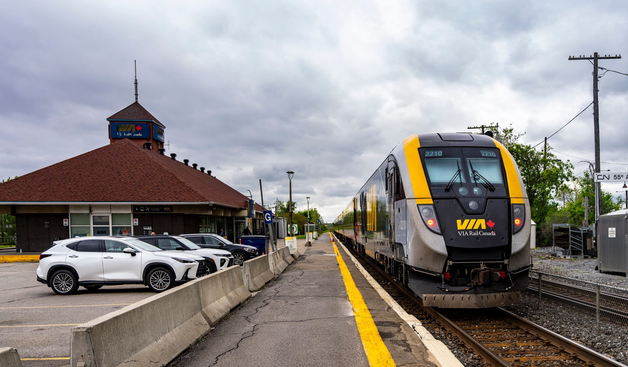 A Via Rail train pulls into a station on a cloudy day