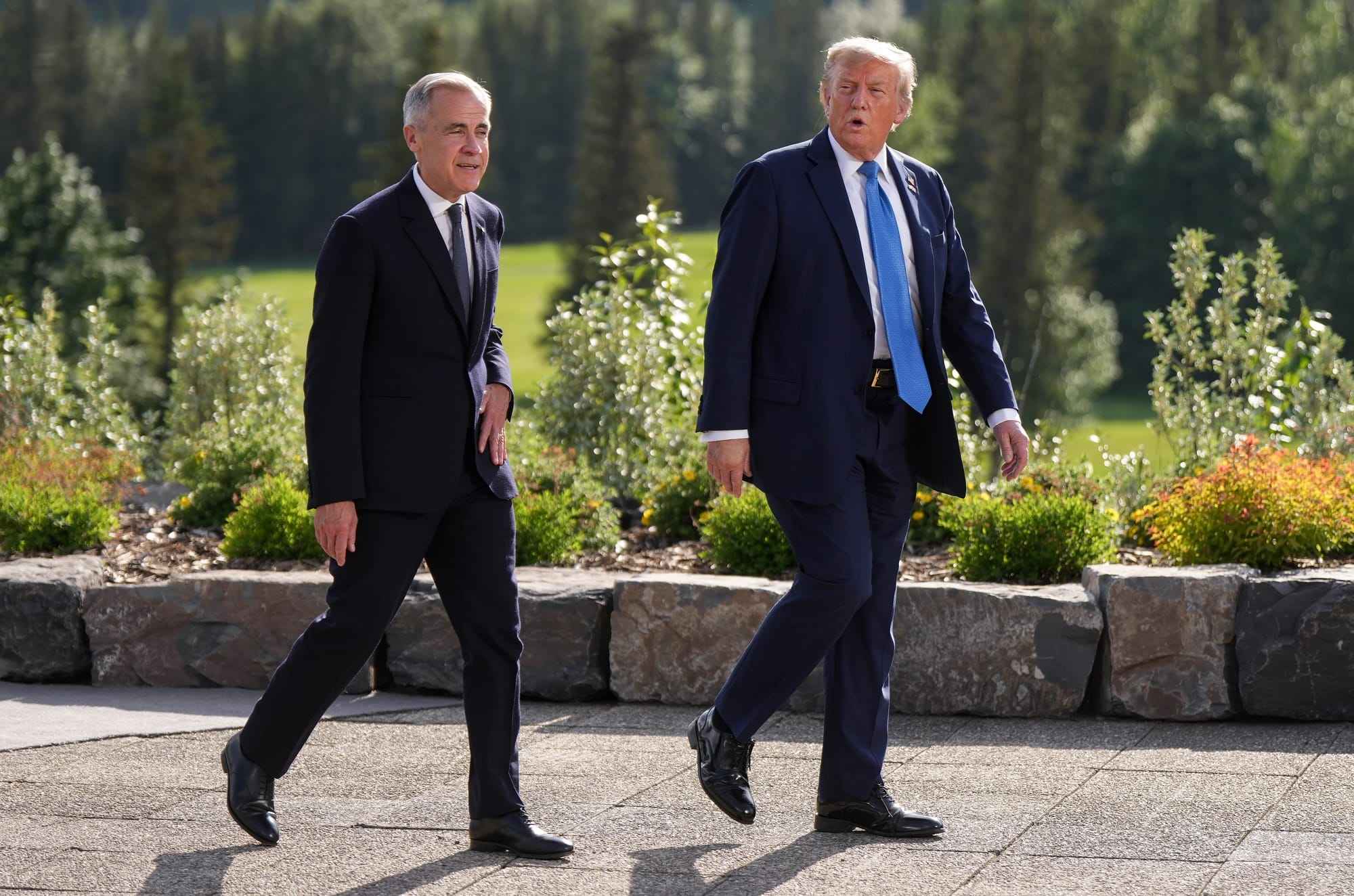 Mark Carney and Donald Trump wear suits as they walk side by side outside