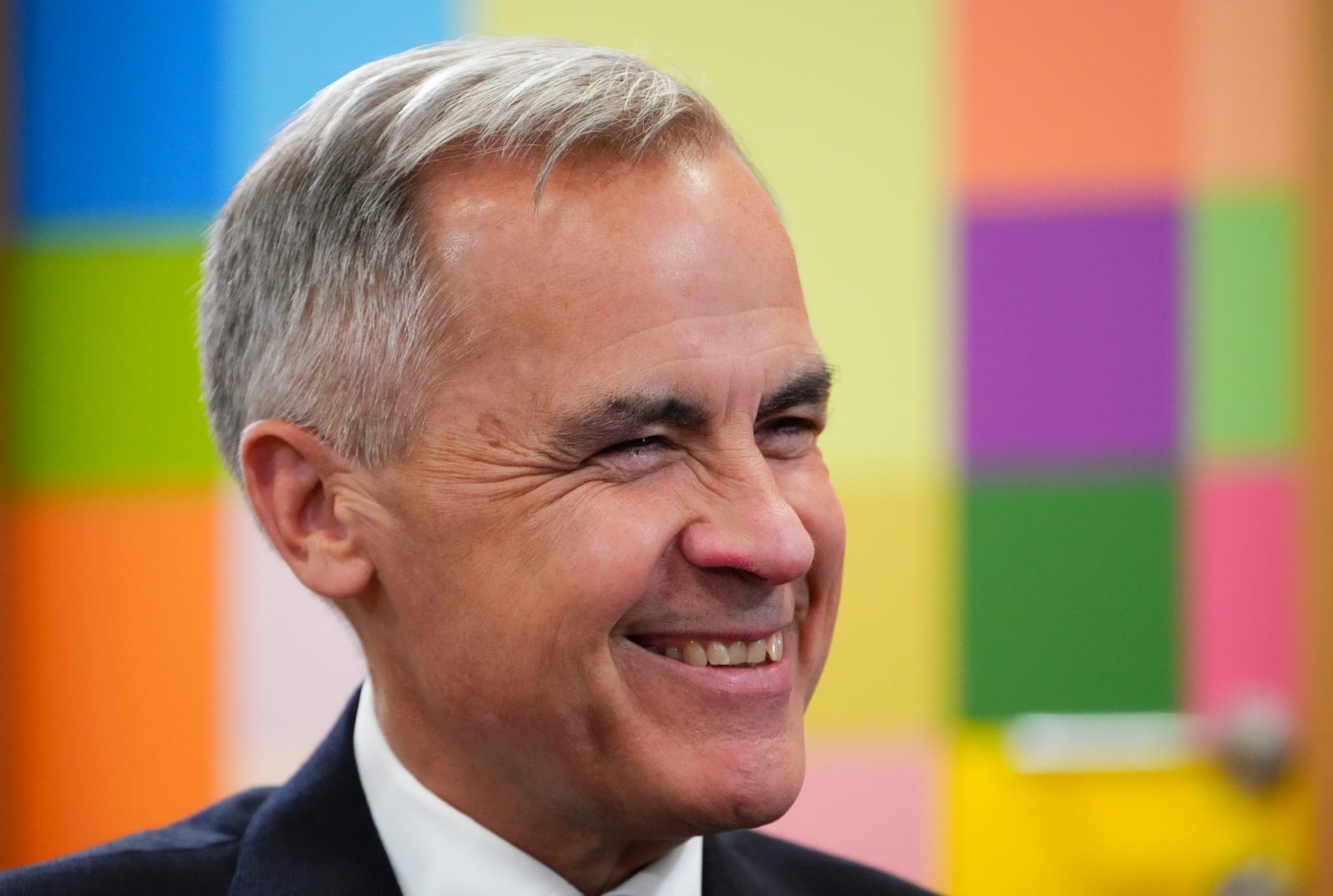 Mark Carney smiles against a colourful backdrop during the Canada EU Summit in Brussels, Belgium on June 23.