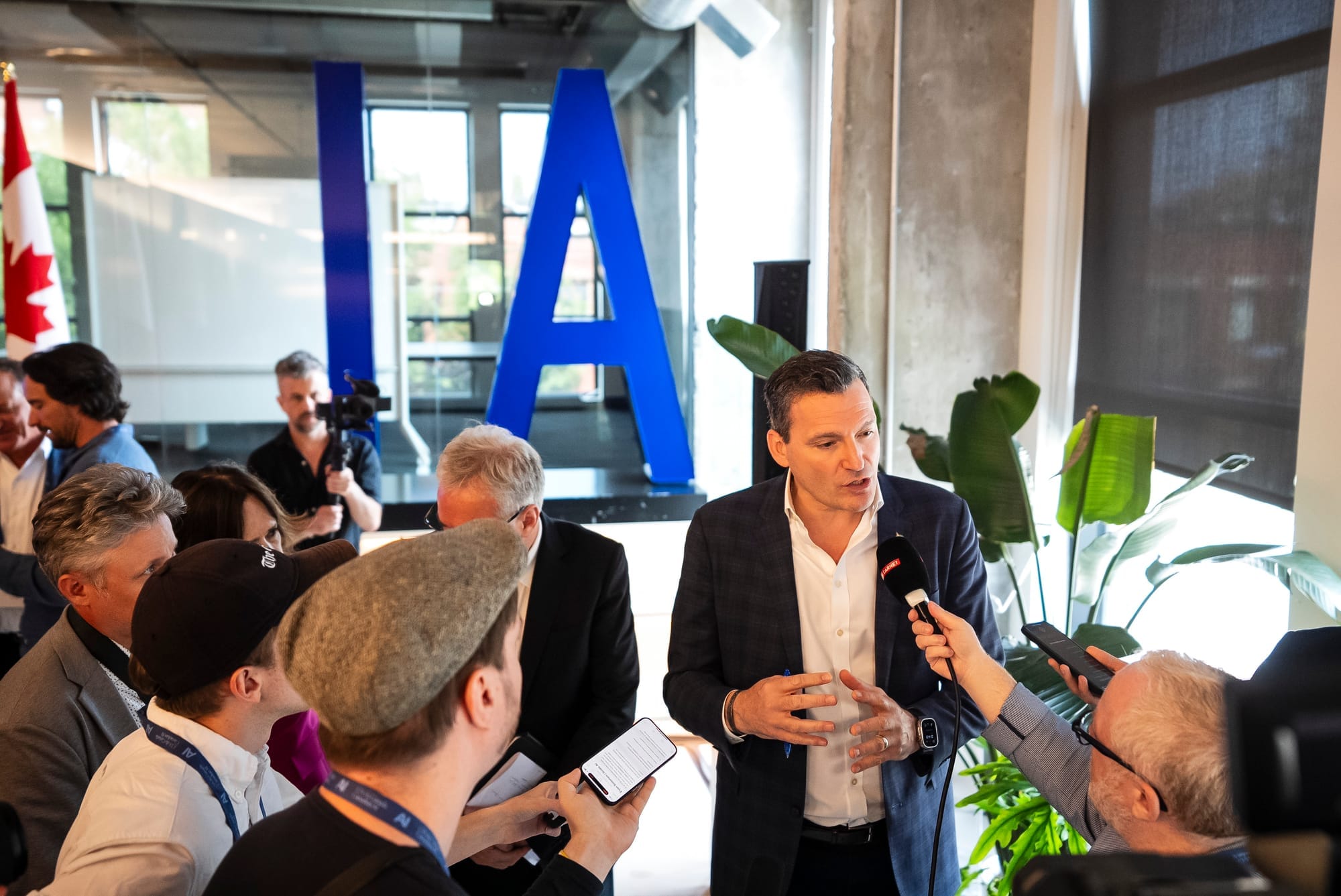 Reporters hold microphones up to Evan Solomon at an office buildi