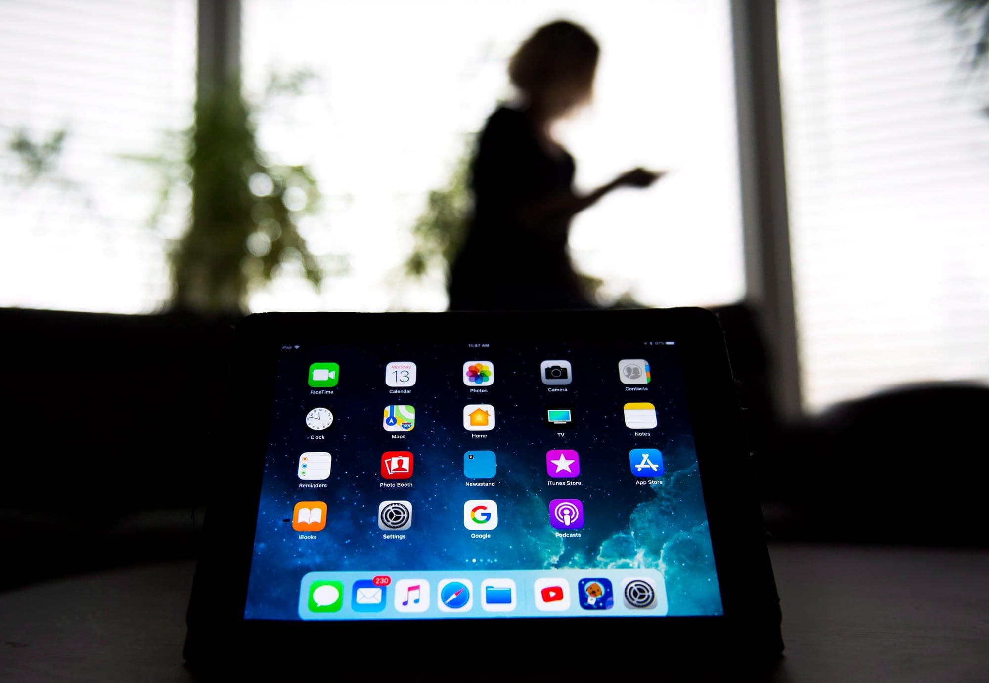 A picture of a tablet device with a blurred, dark image of a woman walking in the background.