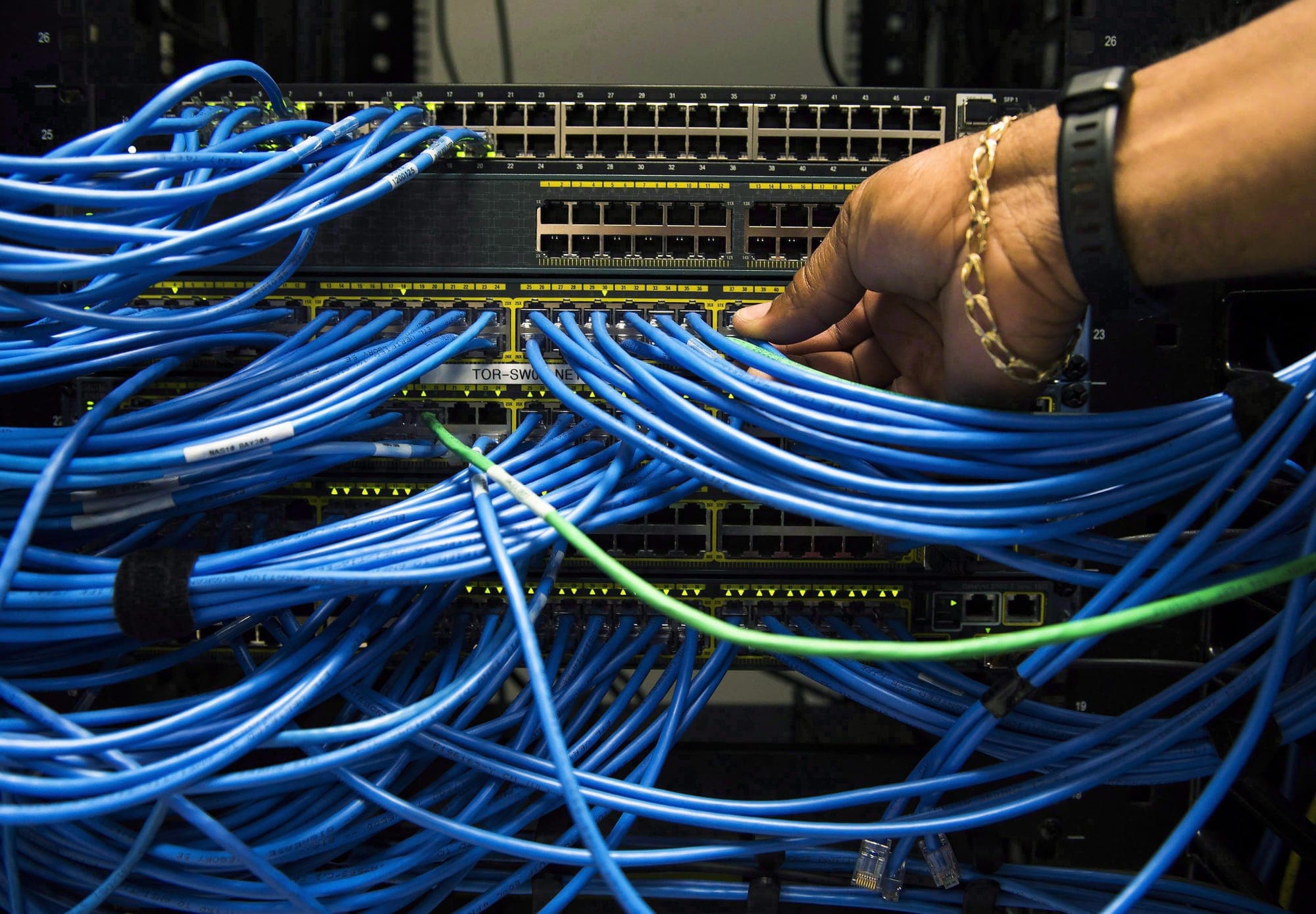 Blue wires feed into a stack of computer servers.